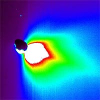 This false-color image shows comet Tempel 1 about 50 minutes after Deep Impact's probe smashed into its surface. The impact site is located on the far side of the comet in this view. The image was taken by the mission's flyby spacecraft as it turned back to face the comet for one last photo opportunity.<br/>
<br/>
The colors represent brightness, with white indicating the brightest materials and black showing the faintest materials. This brightness is a measure of reflected sunlight. The Sun is located to the right, out of the picture.<br/>
<br/>
Because the sunlit portion of the comet is brighter, it appears white. The comet's nucleus is silhouetted against the light reflected from surrounding dust.<br/>
<br/>
The large plume of dust that was kicked up upon impact can be seen as the colorful, drop-shaped object. This plume was very bright, indicating that the comet's surface material must be very fine, like talcum powder.<br/>
<br/>
The blue speck in the upper left corner is a star.<br/>
<br/>
This picture was taken by Deep Impact's high-resolution camera.<br/>
<br/>
Image credit: NASA/JPL-Caltech/UMD