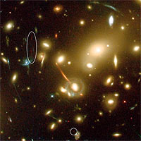 This close-up of the large galaxy cluster Abell 2218 shows how this cluster acts as one of nature’s most powerful ‘gravitational telescopes’ and amplifies and stretches all galaxies lying behind the cluster core (seen as red, orange and blue arcs). Such natural gravitational ‘telescopes’ allow astronomers to see extremely distant and faint objects that could otherwise not be seen. 
<P>
A new galaxy (split into two ‘images’ marked with an ellipse and a circle) was detected in this image taken with the Advanced Camera for Surveys on board the NASA/ESA Hubble Space Telescope. The extremely faint galaxy is so far away that its visible light has been stretched into infrared wavelengths, making the observations particularly difficult. 
<P>
The galaxy may have set a new record in being the most distant known galaxy in the Universe. Located an estimated 13 billion light-years away (z~7), the object is being viewed at a time only 750 million years after the big bang, when the Universe was barely 5 percent of its current age. 
<P>
In the image the distant galaxy appears as multiple ‘images’, an arc (left) and a dot (right), as its light is forced along different paths through the cluster’s complex clumps of mass (the yellow galaxies) where the magnification is quite large. 
<P>
The colour of the different lensed galaxies in the image is a function of their distances and galaxy types. The orange arc is for instance an elliptical galaxy at moderate redshift (z=0.7) and the blue arcs are star forming galaxies at intermediate redshift (z between 1 and 2.5). 
<P>
Credits: European Space Agency, NASA, J.-P. Kneib (Observatoire Midi-Pyrénées) and R. Ellis (Caltech)
