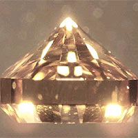 This photograph shows a synthetic brilliant cut single-crystal diamond grown by chemical vapor deposition, CVD. About 2.5 mm high, this crystal was grown in about 1 day at Carnegie. The very bottom (table) of the crystal is a type 1b seed: hence the yellow tint which is due to internal reflection (the CVD diamond is transparent). [C.S. Yan et al., Physica Status Solidi (a) 201,R25 (2004)(PDF 288KB)]. The researchers have also reported that these CVD diamonds are capable of easily generating ultrahigh pressures to at least 200 GPa.[W.L. Mao et al., Appl. Phys. Lett. 83, 5190 (2003)(PDF 288KB)].
Image copyright: Physica Status Solidi.
