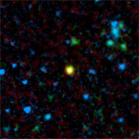 This false-color image from NASA's Spitzer Space Telescope shows a distant galaxy (yellow) that houses a quasar, a super-massive black hole circled by a ring, or torus, of gas and dust.<br/>
<br/>
Credit: NASA