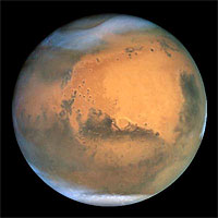 Frosty white water ice clouds and swirling orange dust storms above a vivid rusty landscape reveal Mars as a dynamic planet in this sharpest view ever obtained by an Earth-based telescope. The Earth-orbiting Hubble telescope snapped this picture on June 26, when Mars was approximately 43 million miles (68 million km) from Earth - its closest approach to our planet since 1988. Hubble can see details as small as 10 miles (16 km) across. Especially striking is the large amount of seasonal dust storm activity seen in this image. One large storm system is churning high above the northern polar cap [top of image], and a smaller dust storm cloud can be seen nearby. Another large duststorm is spilling out of the giant Hellas impact basin in the Southern Hemisphere [lower right]. 
<P>
Credits: NASA and The Hubble Heritage Team (STScI/AURA)