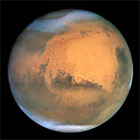 Frosty white water ice clouds and swirling orange dust storms above a vivid rusty landscape reveal Mars as a dynamic planet in this sharpest view ever obtained by an Earth-based telescope. The Earth-orbiting Hubble telescope snapped this picture on June 26, when Mars was approximately 43 million miles (68 million km) from Earth - its closest approach to our planet since 1988. Hubble can see details as small as 10 miles (16 km) across. Especially striking is the large amount of seasonal dust storm activity seen in this image. One large storm system is churning high above the northern polar cap [top of image], and a smaller dust storm cloud can be seen nearby. Another large duststorm is spilling out of the giant Hellas impact basin in the Southern Hemisphere [lower right]. 
<P>
Credits: NASA and The Hubble Heritage Team (STScI/AURA)