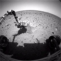 This image shows the Mars Exploration Rover Spirit probing its first target rock, Adirondack. At the time this picture was snapped, the rover had begun analyzing the rock with the alpha particle X-ray spectrometer located on its robotic arm. This instrument uses alpha particles and X-rays to determine the elemental composition of martian rocks and soil. The image was taken by the rover's hazard-identification camera.
<P>
Image Credit: NASA/JPL
