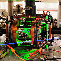 <p>
	Composite photo of microwave apparatus used in NIST quantum computing experiments. A pair of ions (electrically charged atoms) are trapped by electric fields and manipulated with microwaves inside a glass chamber at the center of the apparatus. The chamber is illuminated by a green light-emitting diode for visual effect. An ultraviolet laser beam used to cool the ions and detect their quantum state is colorized to appear blue.</p>
<p>
	Credit: Y. Colombe/NIST</p>
