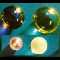 REAl glass is made of Rare Earth oxides, Aluminum oxide and small amounts of silicon dioxide. A company made these samples using static electricity to suspend molten materials so they are melted and cooled without coming in to contact with contaminating containers. The largest sphere, far right, is 3.5 millimeters. To create the new family of glasses, Containerless Research Inc., Evanston, Ill., used containerless processing in its company facilities and at NASA's Marshall Space Flight Center in Huntsville, Ala. (Containerless Research Inc.)

