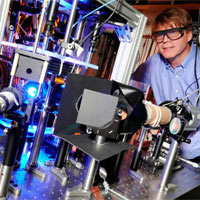 <p>
	Michael Chapman, a professor in the School of Physics at Georgia Tech, poses with optical equipment in his laboratory. Chapman’s research team is exploring squeezed states using atoms of Bose-Einstein condensates. (Click image for high-resolution version. Credit: Gary Meek)</p>
