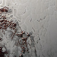 <p>Close-up of Sputnik Planum shows the slowly overturning cells of nitrogen ice. Boulders of water ice and methane debris (red) that have broken off hills surrounding the heart have collected at the boundaries of the cells. (Photo: NASA/Johns Hopkins University Applied Physics Laboratory/Southwest Research Institute)</p>
