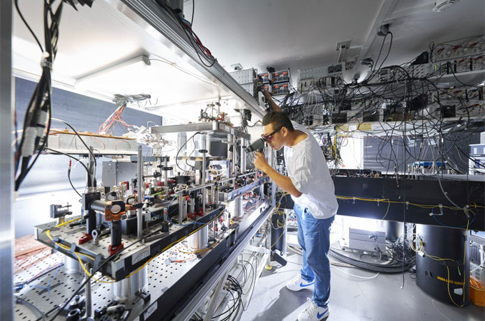 <p>Physicist Wei Zhang, one of the study's first authors, checks the experimental setup in Harald Weinfurter's lab.<br />
© Jan Greune / LMU</p>
